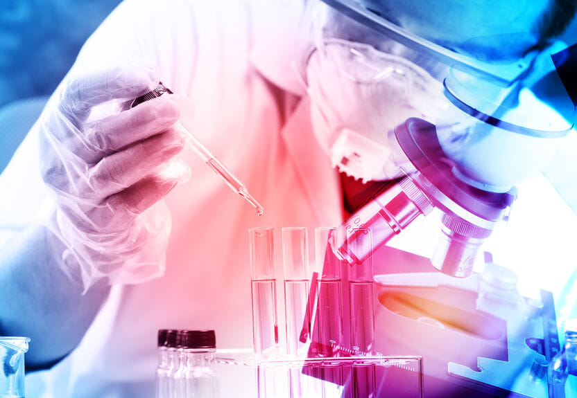 Scientifique travaillant avec microscope et tubes à essai.