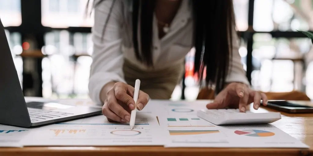 Femme analysant des graphiques financiers avec ordinateur et calculatrice
